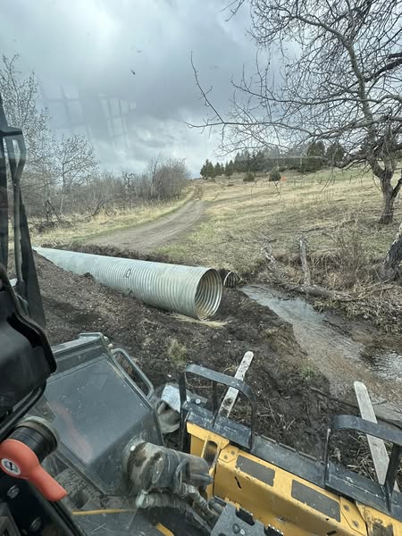 Excavation equipment and culvert pipe near muddy road during drainage work in Helena MT