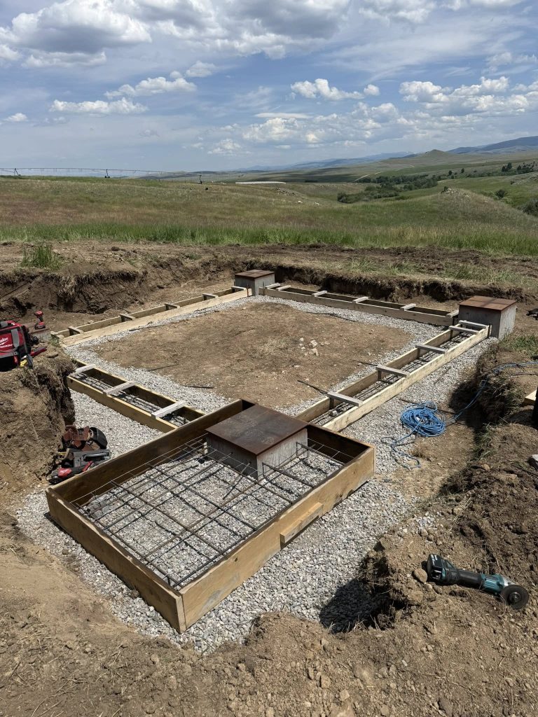 Wooden forms and rebar layout for a foundation slab on a rural Montana hillside