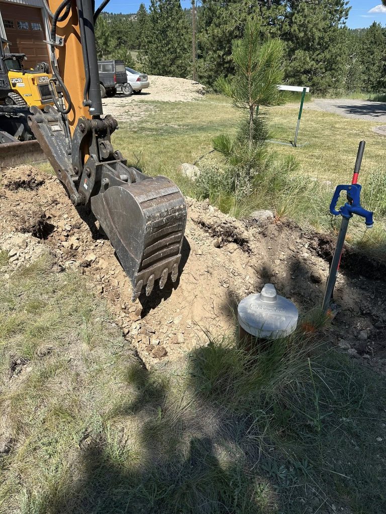 Excavator digging trench for utility line or septic system on a residential property in Helena, Montana
