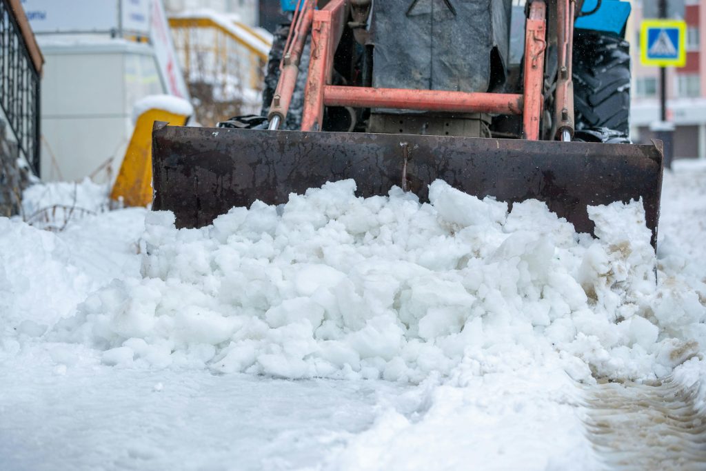 Compact Loader Clearing Slushy Snow from Urban Walkway