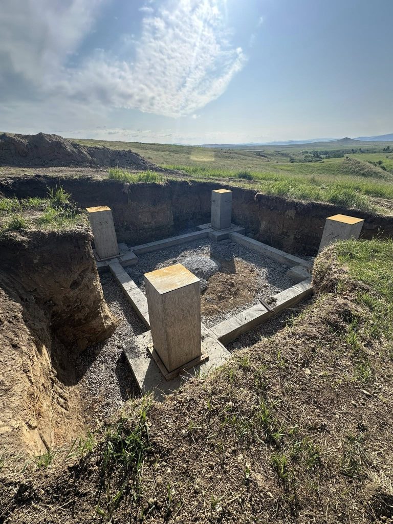 Excavated pier footings with wooden forms in open field near Helena MT construction site